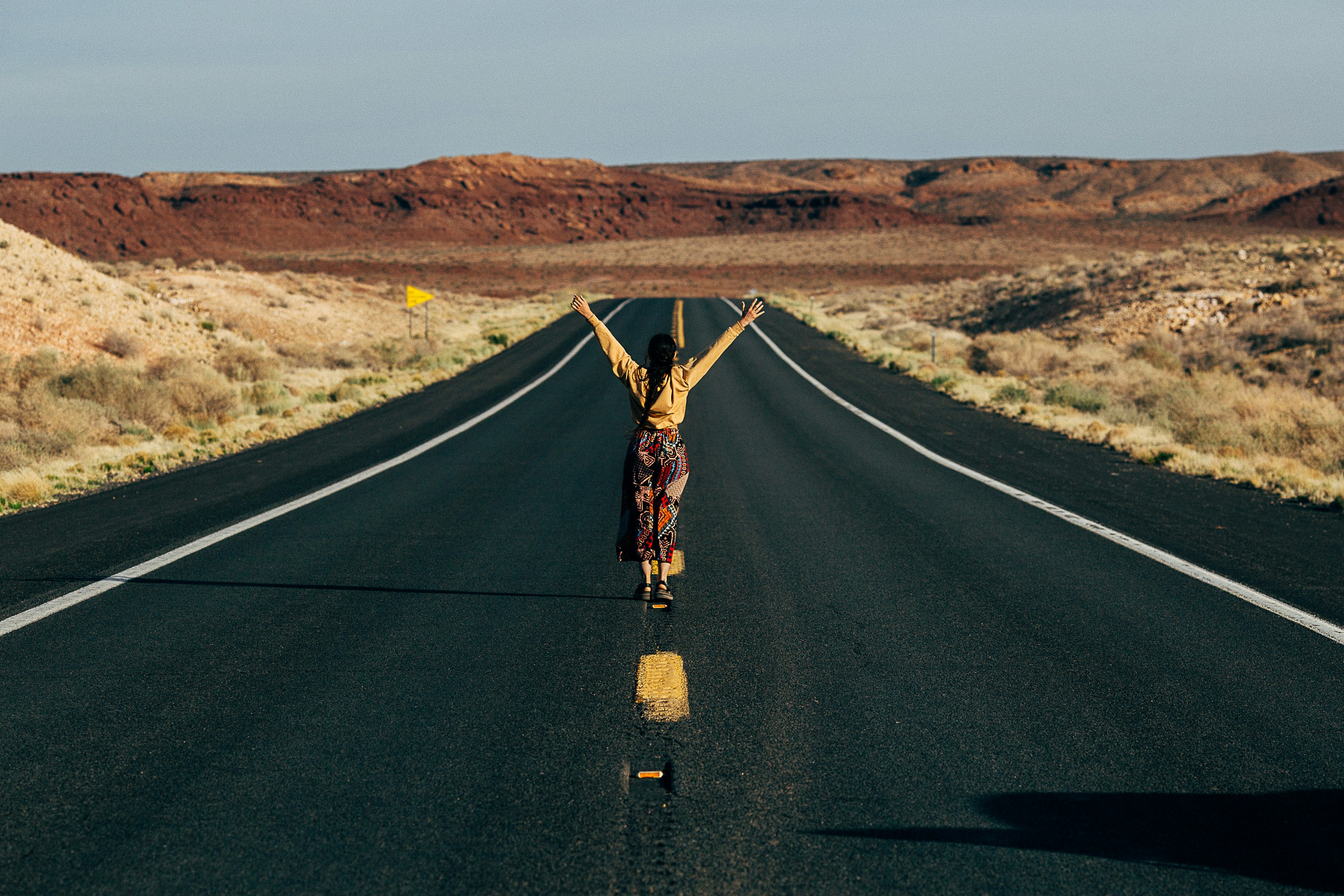 man in black shirt and brown pants standing on black asphalt road during daytime